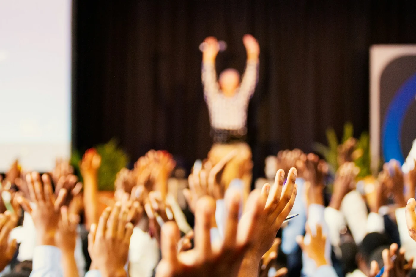 Un public lève la main dans une salle de conférence